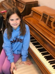 Cute girl child wearing blue color shirt sitting next to piano